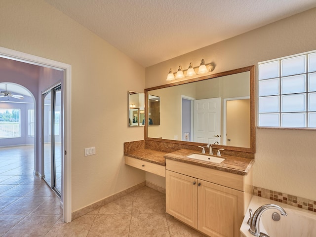 bathroom with a washtub, ceiling fan, tile patterned flooring, vanity, and a textured ceiling