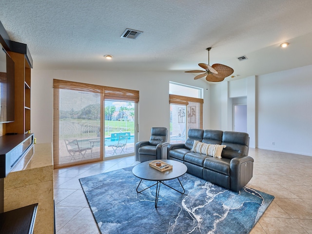 living room featuring lofted ceiling, ceiling fan, a textured ceiling, and light tile patterned flooring