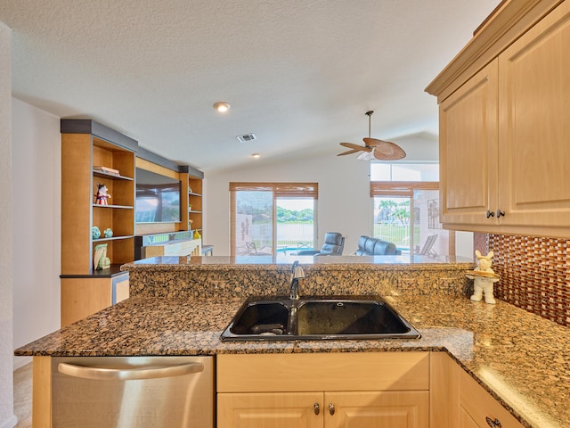 kitchen featuring lofted ceiling, light brown cabinetry, sink, stainless steel dishwasher, and kitchen peninsula