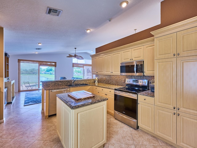 kitchen featuring sink, a center island, vaulted ceiling, kitchen peninsula, and stainless steel appliances