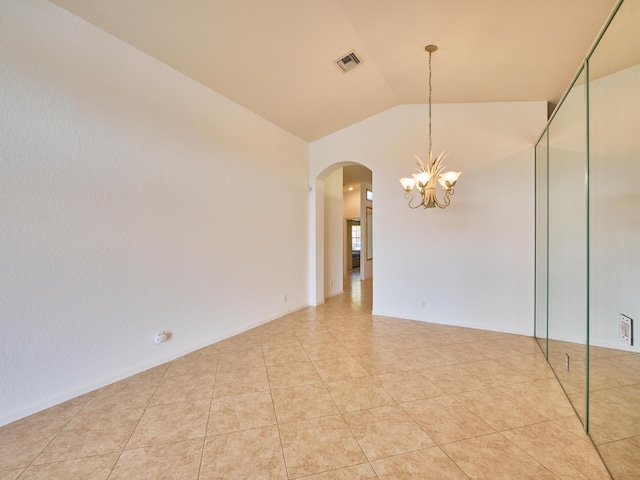 empty room featuring light tile patterned flooring, lofted ceiling, and a chandelier