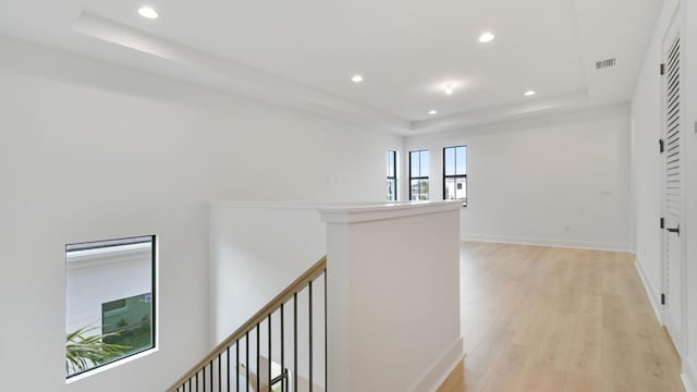 corridor with a raised ceiling and light hardwood / wood-style flooring