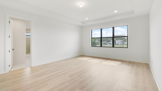 empty room with a tray ceiling and light wood-type flooring