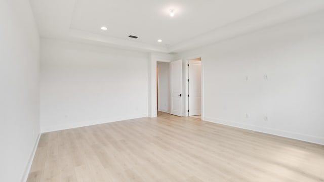 spare room with light hardwood / wood-style flooring and a tray ceiling