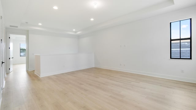 empty room with light hardwood / wood-style flooring and a raised ceiling