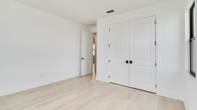 unfurnished bedroom with light hardwood / wood-style flooring and a closet