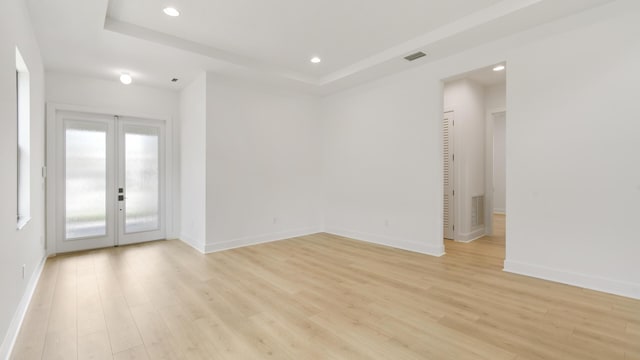 unfurnished room with light hardwood / wood-style flooring and a raised ceiling