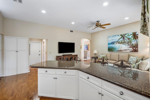 kitchen with ceiling fan, dark stone countertops, wood-type flooring, a textured ceiling, and white cabinets