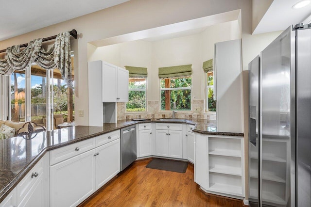 kitchen with a healthy amount of sunlight, appliances with stainless steel finishes, dark stone counters, and white cabinets