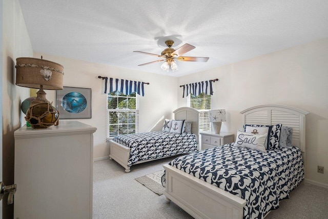 bedroom with ceiling fan, light colored carpet, and a textured ceiling