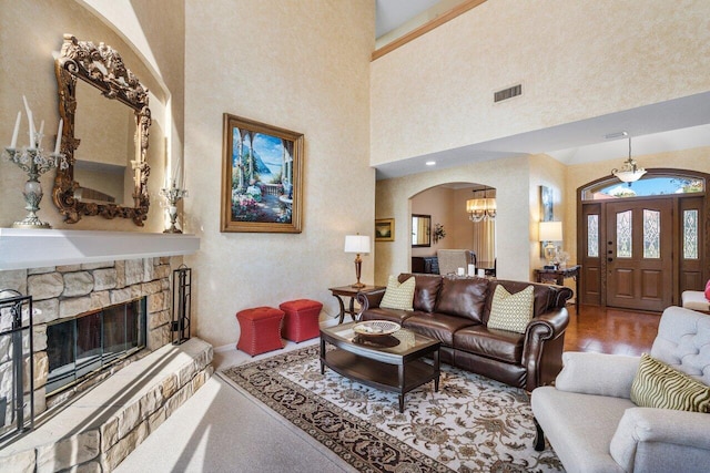 living room with a high ceiling, hardwood / wood-style floors, a notable chandelier, and a fireplace