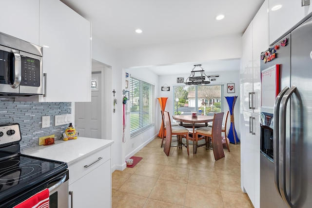 kitchen featuring appliances with stainless steel finishes, decorative light fixtures, white cabinets, backsplash, and light tile patterned floors