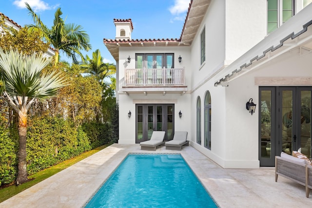 back of house featuring a patio, a balcony, and french doors