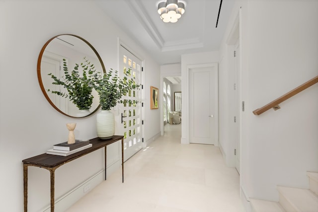 corridor featuring a notable chandelier and a tray ceiling