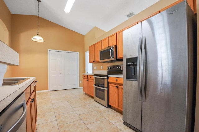 kitchen featuring pendant lighting, sink, stainless steel appliances, light tile patterned flooring, and vaulted ceiling