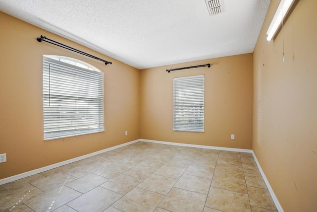 tiled spare room featuring a textured ceiling