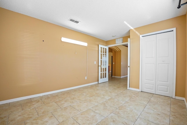 unfurnished bedroom with french doors, light tile patterned floors, and a closet