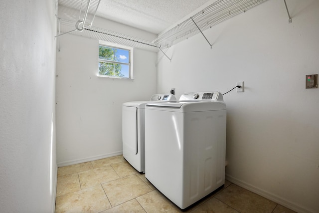 clothes washing area featuring washer and clothes dryer, a textured ceiling, and light tile patterned flooring