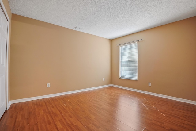 spare room with hardwood / wood-style floors and a textured ceiling