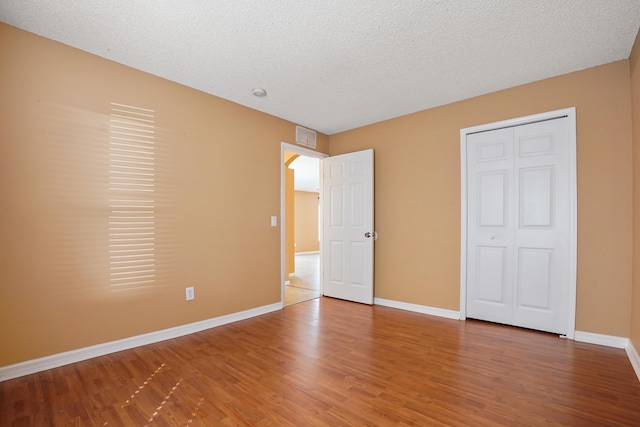 unfurnished bedroom featuring wood-type flooring, a closet, and a textured ceiling