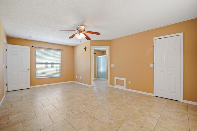 tiled empty room featuring a textured ceiling and ceiling fan