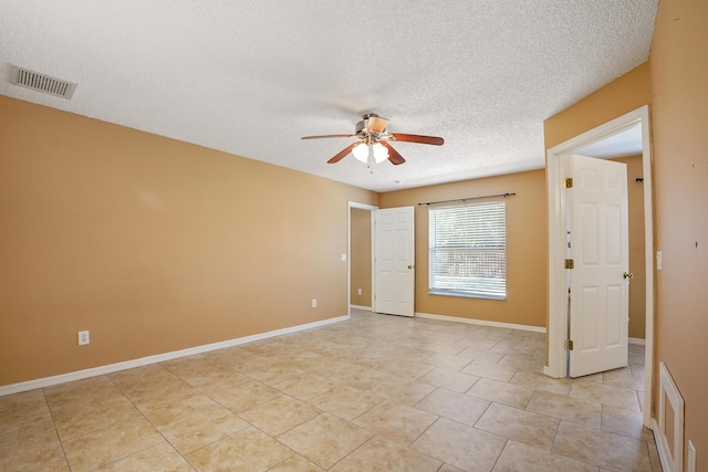 spare room with ceiling fan, light tile patterned floors, and a textured ceiling