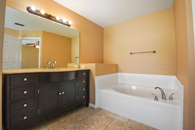 bathroom with tiled tub, vanity, and tile patterned floors