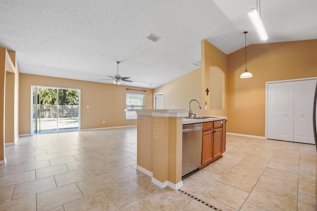 kitchen with lofted ceiling, decorative light fixtures, light tile patterned floors, dishwasher, and a kitchen island with sink