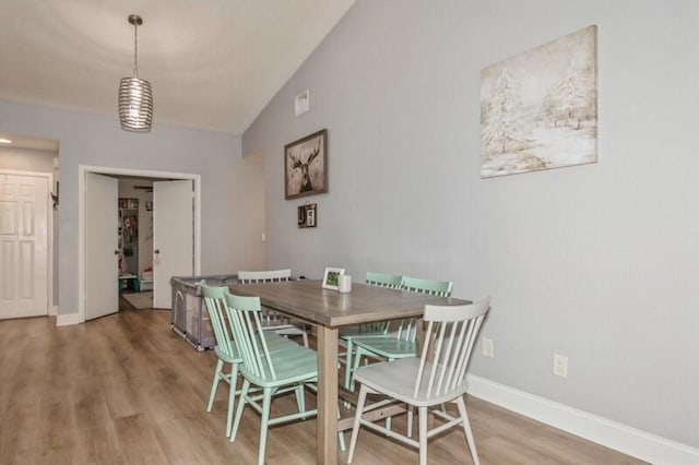 dining area featuring hardwood / wood-style flooring and vaulted ceiling