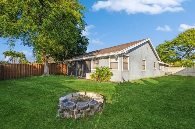 rear view of property featuring a yard and a fire pit