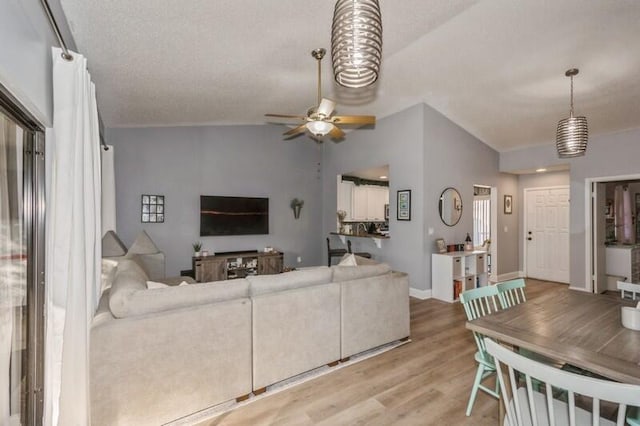 living room with lofted ceiling, light wood-type flooring, and ceiling fan