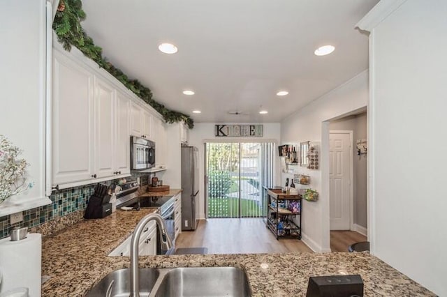 kitchen featuring sink, appliances with stainless steel finishes, white cabinetry, backsplash, and light stone counters