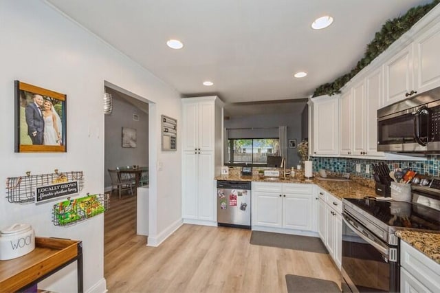 kitchen with dark stone countertops, stainless steel appliances, and white cabinets