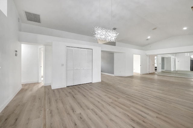 unfurnished living room featuring a notable chandelier, vaulted ceiling, and light hardwood / wood-style floors