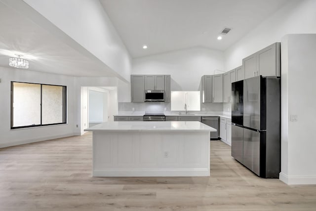 kitchen with gray cabinetry, sink, stainless steel appliances, and a center island