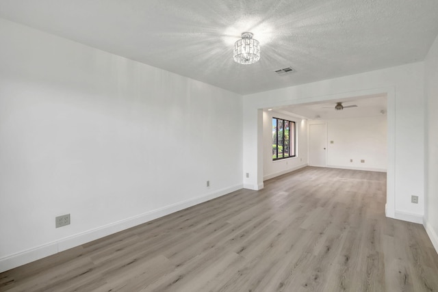 unfurnished room featuring ceiling fan with notable chandelier, a textured ceiling, and light hardwood / wood-style flooring