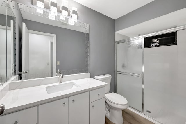 bathroom with walk in shower, vanity, toilet, and hardwood / wood-style floors