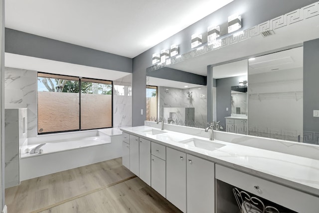 bathroom featuring hardwood / wood-style flooring, vanity, and a tub to relax in