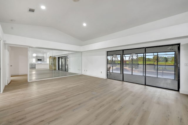 spare room with vaulted ceiling and light wood-type flooring