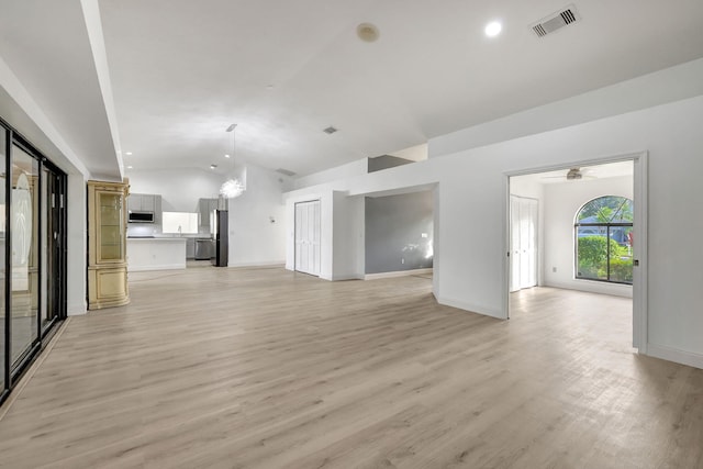 unfurnished living room with lofted ceiling and light wood-type flooring