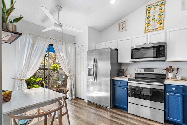 kitchen featuring blue cabinets, vaulted ceiling, appliances with stainless steel finishes, and a textured ceiling