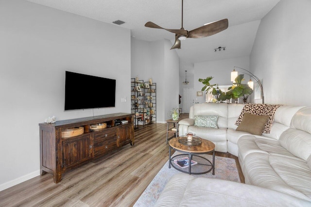 living room featuring lofted ceiling, light hardwood / wood-style floors, and ceiling fan