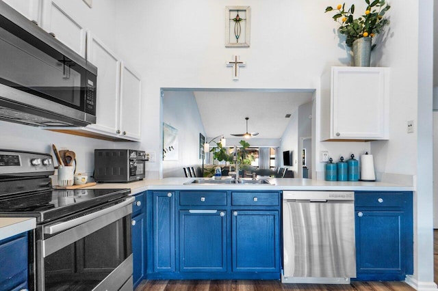 kitchen with white cabinetry, lofted ceiling, stainless steel appliances, and blue cabinetry