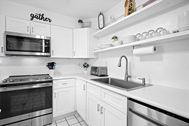 kitchen featuring sink, stainless steel dishwasher, white cabinets, and light tile patterned floors