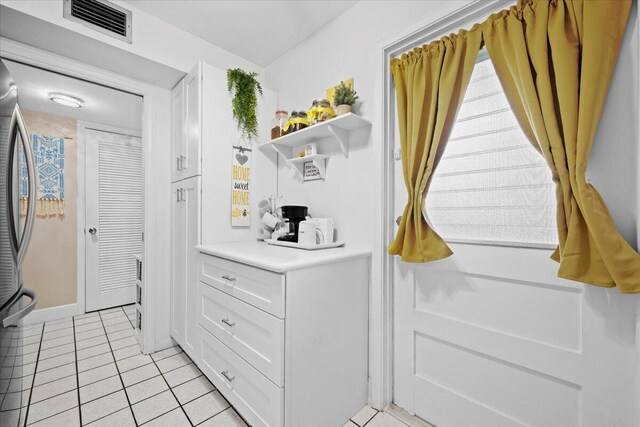 kitchen featuring white cabinetry, stainless steel appliances, and light tile patterned flooring