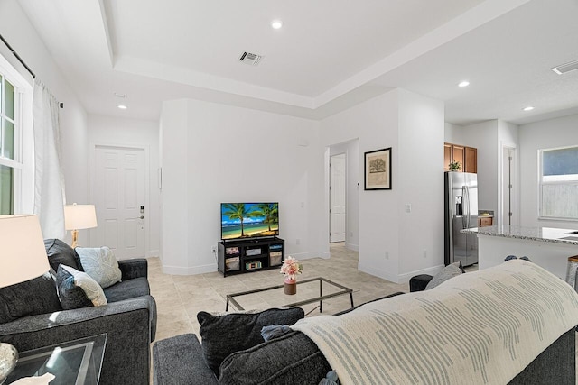 tiled living room featuring a raised ceiling