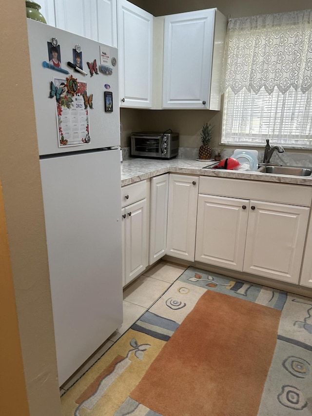 kitchen featuring sink, light tile patterned floors, white cabinets, and white fridge