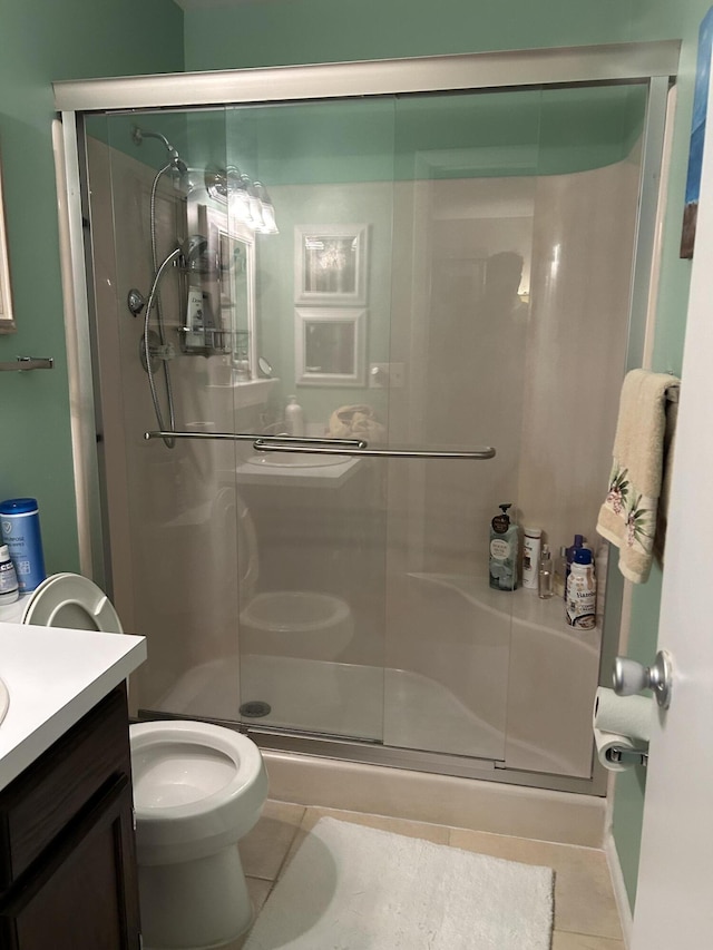 bathroom featuring tile patterned flooring, vanity, an enclosed shower, and toilet