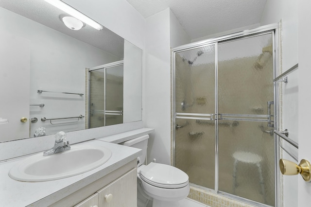 bathroom featuring vanity, toilet, a shower with shower door, and a textured ceiling