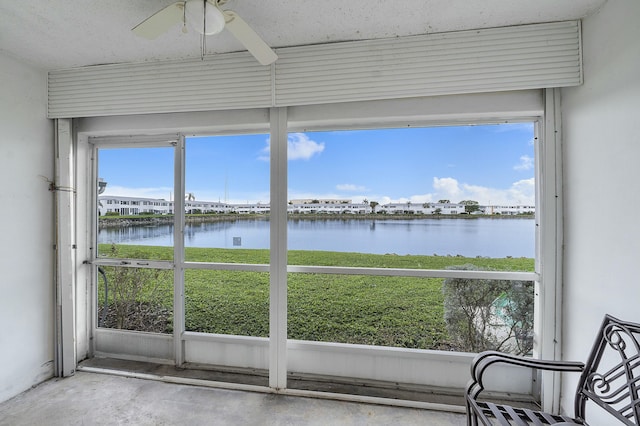 unfurnished sunroom with a water view and ceiling fan